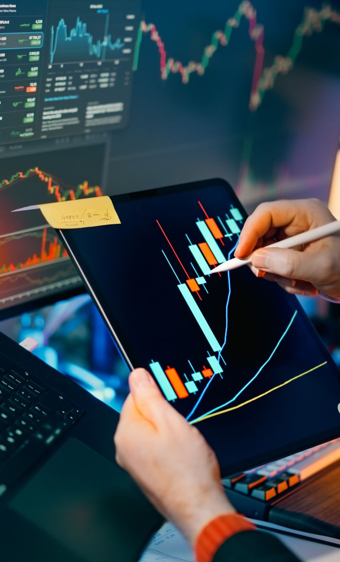 Offerings Person using a tablet to analyze financial charts for trading insights. Perfect for finance and technology themes.