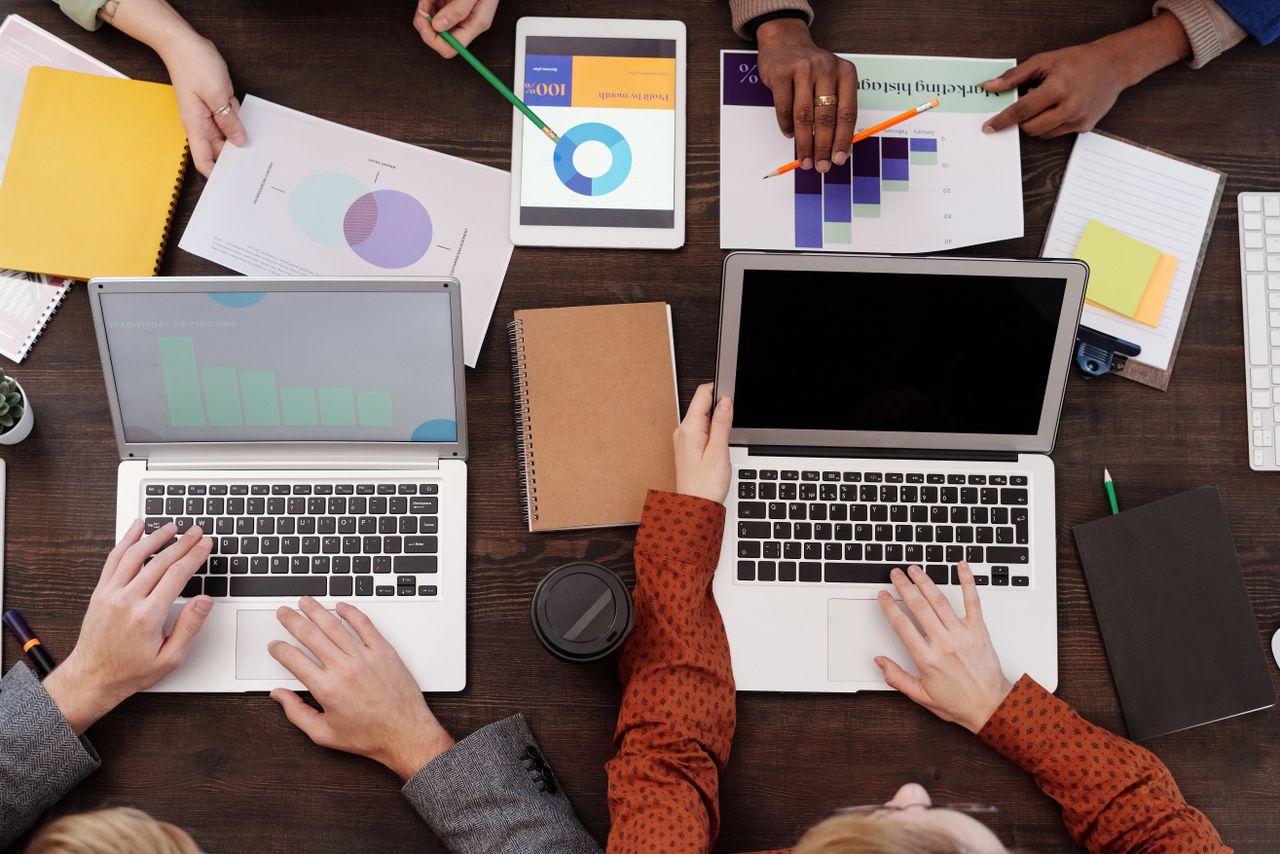 Portfolio Overhead view of a team discussing digital marketing strategies with laptops and charts.