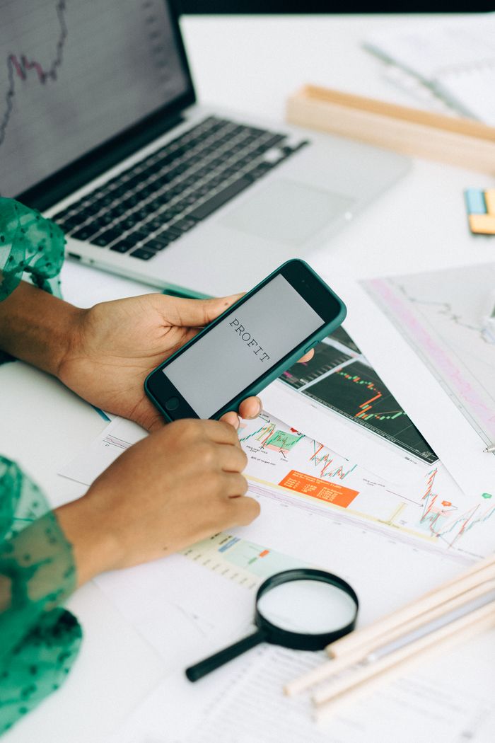 Offerings Close-up of a woman using a smartphone to analyze business data with charts and graphs.